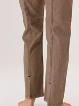 Jean de corte recto confeccionado en denim azul oscuro, con costuras a la vista en color rojo contrastante. Presenta un diseño de tiro alto con bolsillos frontales y cierre de botón.