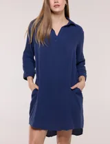 Vestido corto blanco de algodón, marca Dash, con cuello camisero, escote en V y bolsillos laterales. Presenta mangas tres cuartos y calce holgado con ruedo irregular.