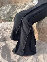 Pantalón negro de tiro alto, corte ancho y fluido, con cintura elástica.