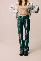 Pantalón de cuero de tiro medio y silueta recta levemente acampanada, color azul marino, con cierre frontal y recortes laterales intervenidos con pasacintas entrelazadas en contraste.