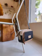 Bandolera rectangular combinada en color negro, beige y blanco, con correa larga regulable y bolsillo exterior con cierre.