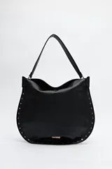 Bolso negro tipo hobo de símil cuero con textura suave y tachas metálicas en los bordes.