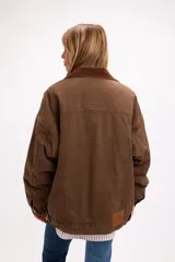 Campera de denim en tono marrón con diseño vintage, corte relajado, cuello de pana y bolsillos delanteros con solapa.