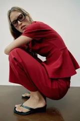 Top peplum confeccionado en hilatura de algodón de color bordó, con escote en V pronunciado, mangas cortas abullonadas y bajo con vuelo.