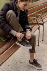 Championes urbanos con diseño de paneles en tonos verde oliva, negro y gris. Presentan una combinación de texturas que incluye cuero liso, gamuza y un panel con estampado de piel de serpiente en el talón. Cuentan con cordones negros y una suela de plataforma blanca con textura acanalada.