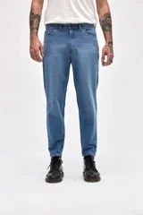 Jean de corte mom en color azul medio, con diseño de cinco bolsillos, cierre frontal con botón y bragueta, y costuras reforzadas.