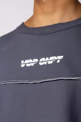 Buzo oversize de corte boxy, confeccionado en algodón rústico de alto gramaje en color beige. Presenta cuello redondo con borde crudo, mangas largas y una estampa frontal con el texto VCP delimitado por líneas horizontales blancas.