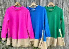 Sweater de punto fucsia con cuello redondo y corte asimétrico con aberturas laterales. Detalle de rib en color beige en cuello, puños y ruedo.