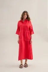 Vestido largo lila de lino, con cuello camisero, mangas cortas, bolsillos frontales con costuras a contratono y aberturas laterales.