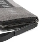 Billetera con cierre de cremallera, diseño color block en tonos de gris y logo estampado en el frente.