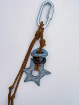 Charm para bolso o accesorios con mosquetón metálico, tejido de macramé en cordón negro y dijes de cerámica esmaltada en tonos violeta y celeste.