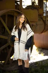 Ruana artesanal de lana merino en color crudo con detalles de líneas horizontales en color marrón chocolate y terminación con flecos en el ruedo.