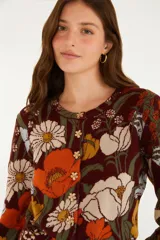 Cardigan de punto color marrón con diseño floral estampado en tonos naranjas, blancos y celestes, escote redondo y cierre frontal de botones con forma de flor.