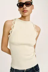 Top negro de punto rib con cuello halter, sin mangas y detalles de encaje a tono en las sisas.