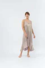 Vestido midi color lila metálico de breteles finos regulables, escote en V y ruedo asimétrico con leve vuelo.