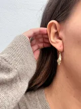 Par de aros colgantes dorados con forma de concha marina.