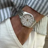 Reloj analógico Casio con caja y malla de acero inoxidable en tono plateado. Presenta una esfera blanca con índices de bastón, manecillas luminiscentes y ventana de calendario a las tres en punto.