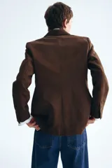 Blazer marrón de botonadura sencilla con acabado cepillado suave, hombreras, solapas de muesca y bolsillos delanteros ribeteados.