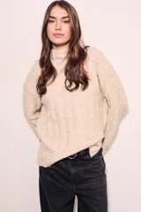 Sweater color crema con cuello alto, tejido de punto con textura y mangas largas con puños acampanados.