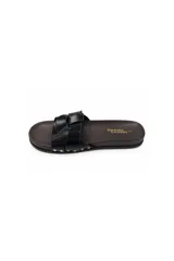 Sandalias planas Daniel Cassin modelo Romi, color negro con tiras cruzadas en el empeine, base de aspecto amaderado y detalles de tachas doradas laterales.