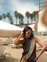 Top negro de lentejuelas con detalle de flecos de rafia en el lateral. Diseño halter con tiras para atar en el cuello.