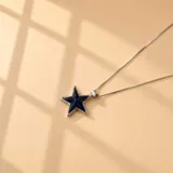 Collar de cadena fina de plata 925 con dije en forma de estrella, con centro de resina color azul oscuro y borde plateado.