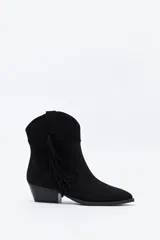 Bota texana de gamuza negra con caña baja, flecos laterales decorativos, costuras estilo western y taco bajo inclinado.