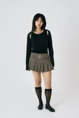 Minifalda plisada con estampado de pata de gallo, cintura caída y cinturón ajustable con detalle de ojales. Confeccionada en mezcla de poliéster y lana suave.