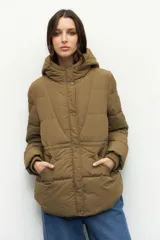 Campera puffer color tostado con capucha, cierre frontal con botones a presión y bolsillos laterales. Presenta diseño acolchado, puños elásticos y ajuste en la cintura.