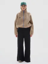 Campera de sherpa color beige con cuello alto, cierre frontal completo en color azul a contratono y bordado en el pecho.