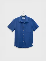 Camisa azul de manga corta confeccionada en algodón ligero con textura waffle. Presenta corte cuadrado, bolsillo en el pecho y botones de coco grabados con el logo de Polonio.