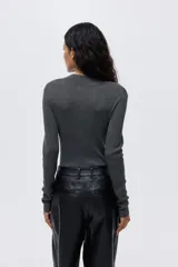 Top de manga larga en tejido de punto acanalado, de corte ajustado, con cuello elevado y tapeta de botones frontal, presentando un diseño con forro interior en contraste.