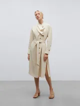 Vestido camisero midi color crema, de lino y viscosa, con cuello chal asimétrico, manga larga con puños abotonados, cierre frontal con botones y cinturón con hebilla forrada.