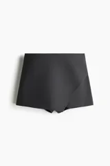 Short pollera de sarga color negro, con diseño cruzado en el frente de corte asimétrico que simula una falda por delante y short por detrás.