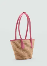 Bolso tipo cesta de fibra natural con detalles en color fucsia, incluyendo doble asa corta y borde superior. Cuenta con cierre de imán interior.