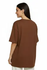 Remera de algodón color beige con cuello redondo y mangas cortas. Presenta un estampado frontal en color blanco con motivos festivos y la frase 'Slice, Sip, Spill'.