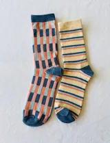 Pack de dos pares de medias de algodón con diseños estampados. Un par presenta un diseño a cuadros en tonos azul, celeste y naranja. El otro par presenta un diseño a rayas horizontales en tonos beige, azul y naranja.