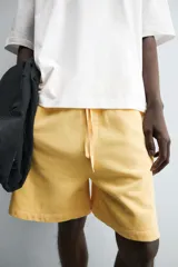 Bermuda de algodón gris con efecto lavado, corte relajado, cintura elástica ajustable con cordón y bolsillos laterales y trasero de vivo.