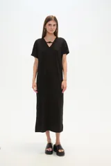 Vestido midi de corte holgado, color negro, con mangas cortas, cuello en V y detalle de cuentas decorativas en el escote.