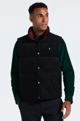 Chaleco reversible de pana, con cierre frontal de botones a presión y cuello alto. Presenta un diseño acolchado con logo bordado en el pecho.