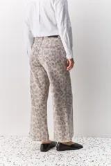 Pantalón de jean tiro medio con corte wide leg y estampado animal print. Presenta costuras verticales frontales y diseño de pierna amplia.