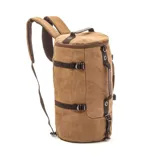 Bolso mochila de diseño cilíndrico confeccionado en tela canvas color marrón. Cuenta con correas acolchadas ajustables, manijas de mano, correas de compresión laterales y cierre superior.