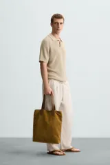 Polo de manga corta, color beige claro, con cuello solapa y cierre frontal de dos botones. Tejido de punto con textura acanalada vertical.