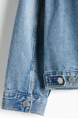 Campera trucker de denim de algodón rígido en color celeste con lavado claro, cuello camisero, cierre frontal de botones metálicos, bolsillos con solapa en el pecho y bolsillos laterales.