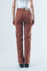 Pantalón de jean tiro alto con corte recto levemente acampanado. Presenta bolsillos delanteros tipo cargo marcados y costuras visibles en color marrón.