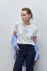 Remera blanca de silueta amplia y calce relajado, confeccionada en tela suave y liviana, con cuello redondo, mangas cortas con vuelta y hombros caídos. Cuenta con un delicado bordado frontal en color azul con la inscripción "LE SOLEIL TOUTE L'ANNÉE sur la Côte d'Azur".