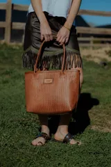 Cartera tipo canasto color marrón, hecha en 100% cuero con diseño tejido. Tiene bolsillo interno, porta llaves y cierre.