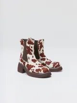 Botas estilo Chelsea de cuero vacuno rojo con grabado texturado tipo paisley, elásticos laterales negros y suela gruesa con taco de 5,5 cm.