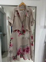Set compuesto por una casaca y un vestido midi de lino color beige con estampado de grandes flores fucsias. La casaca es de mangas largas con puños arremangados y bolsillos frontales con solapa. El vestido es sin mangas, con corte midi y diseño fluido.