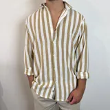 Camisa de corte oversize confeccionada en lino, con diseño de rayas verticales en color tostado y blanco. Presenta cuello clásico, cierre frontal con botones y mangas largas con puños doblados.